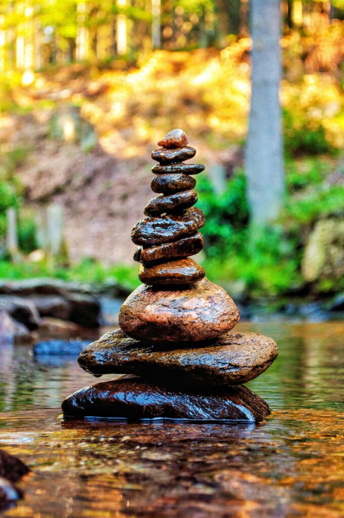 pexels-photo-13887256-13887256 Meditative stone stack in serene forest stream, embodying nature and tranquility.